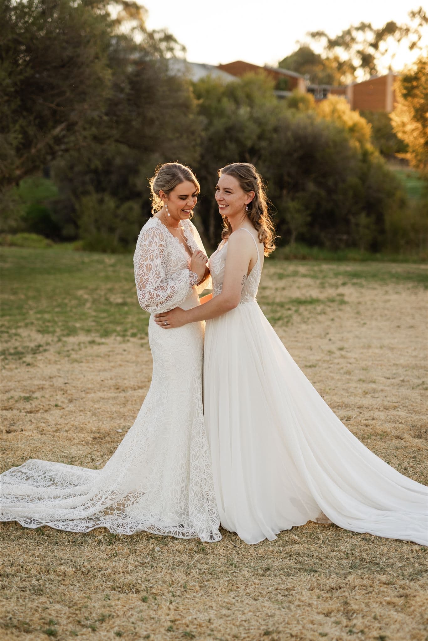 Perth wedding photographer two brides hugging laughing wearing white dresses with warm sunset golden light at Perth wedding