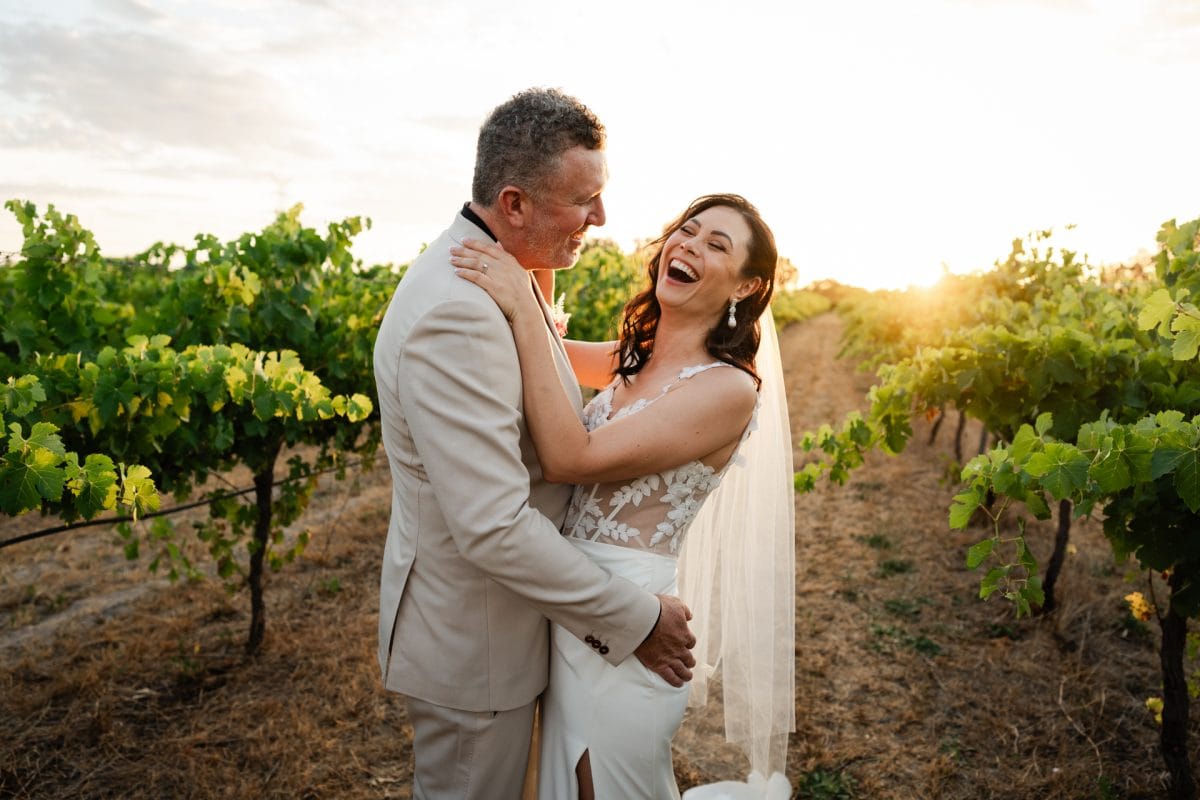 bride and groom laughing amongst vineyards