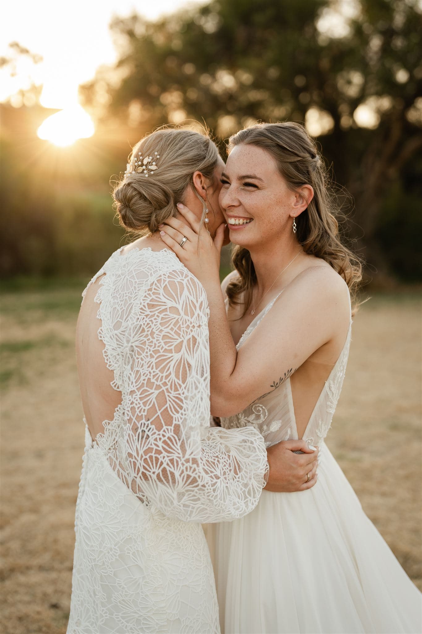 Perth wedding photographer two brides hugging laughing wearing white dresses with warm sunset golden light at Perth wedding