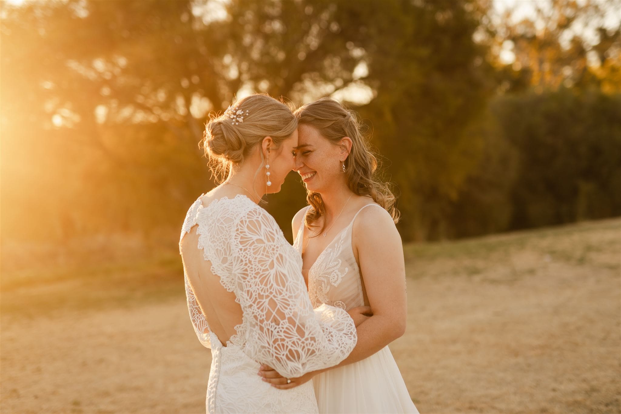 Perth wedding photographer two brides hugging laughing wearing white dresses with warm sunset golden light at Perth wedding