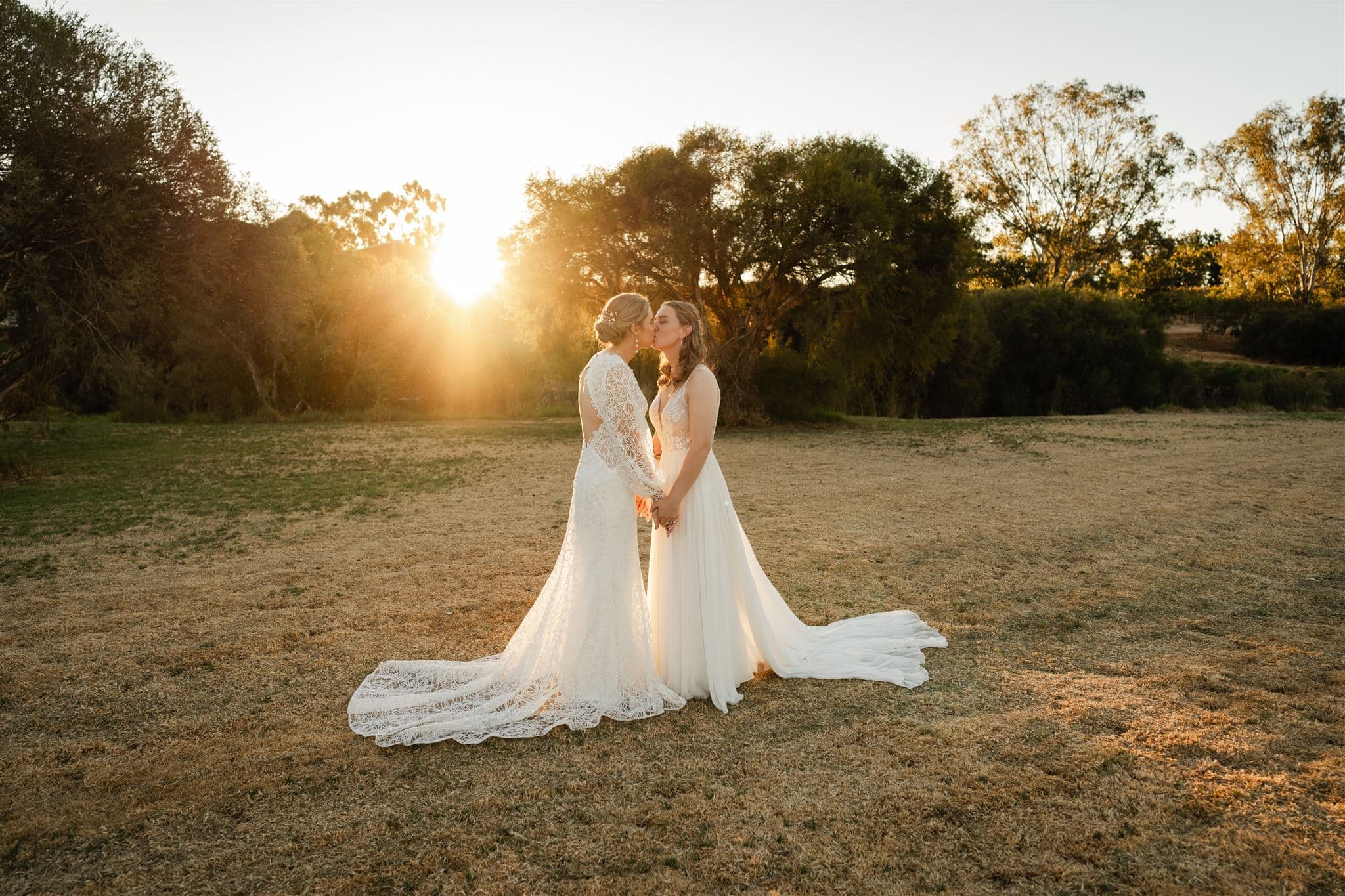 Perth wedding photographer two brides wearing white dresses kissing with warm sunset golden light at Perth wedding