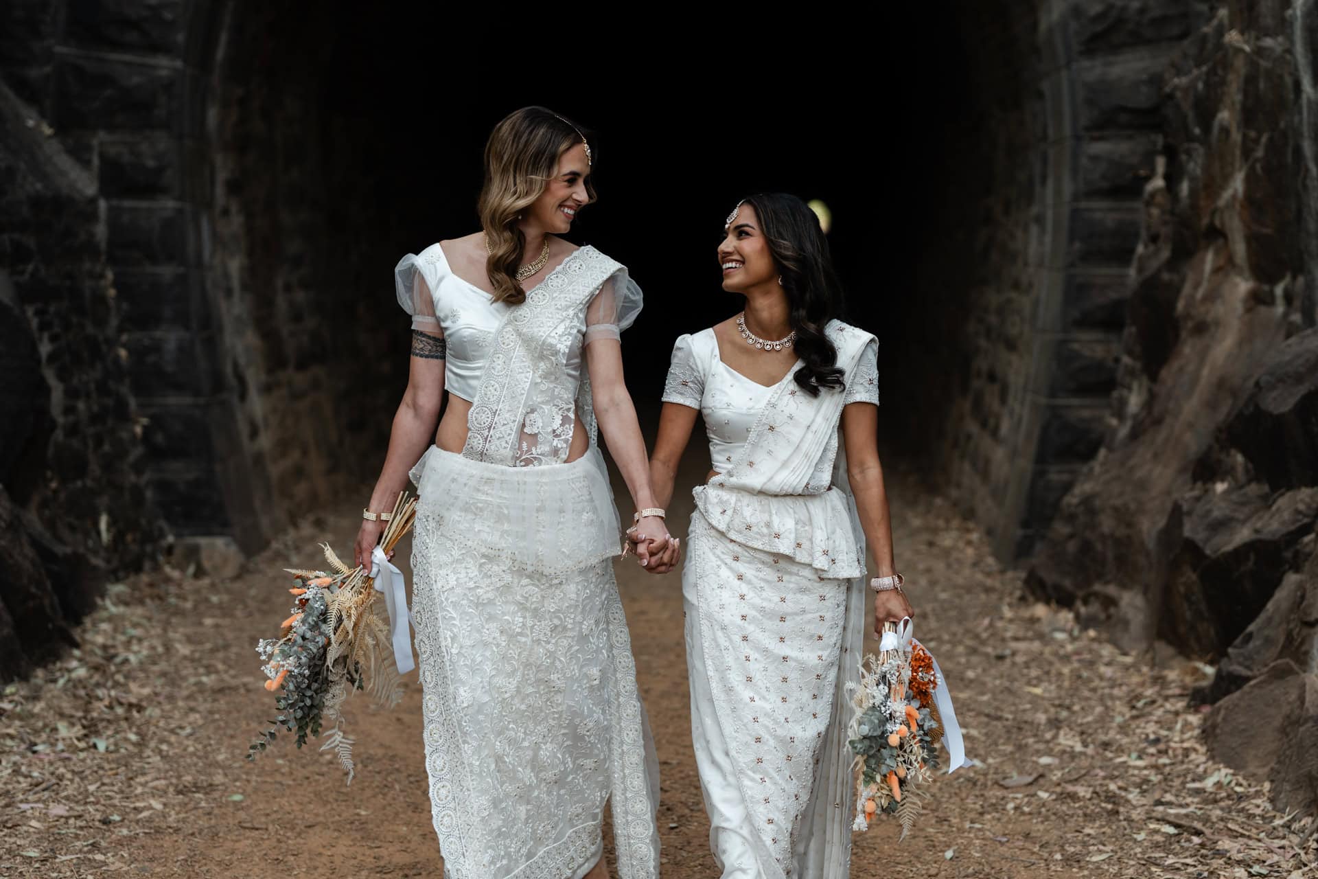 Perth wedding photographer two brides in white sarees walking holding hands smiling at Perth wedding