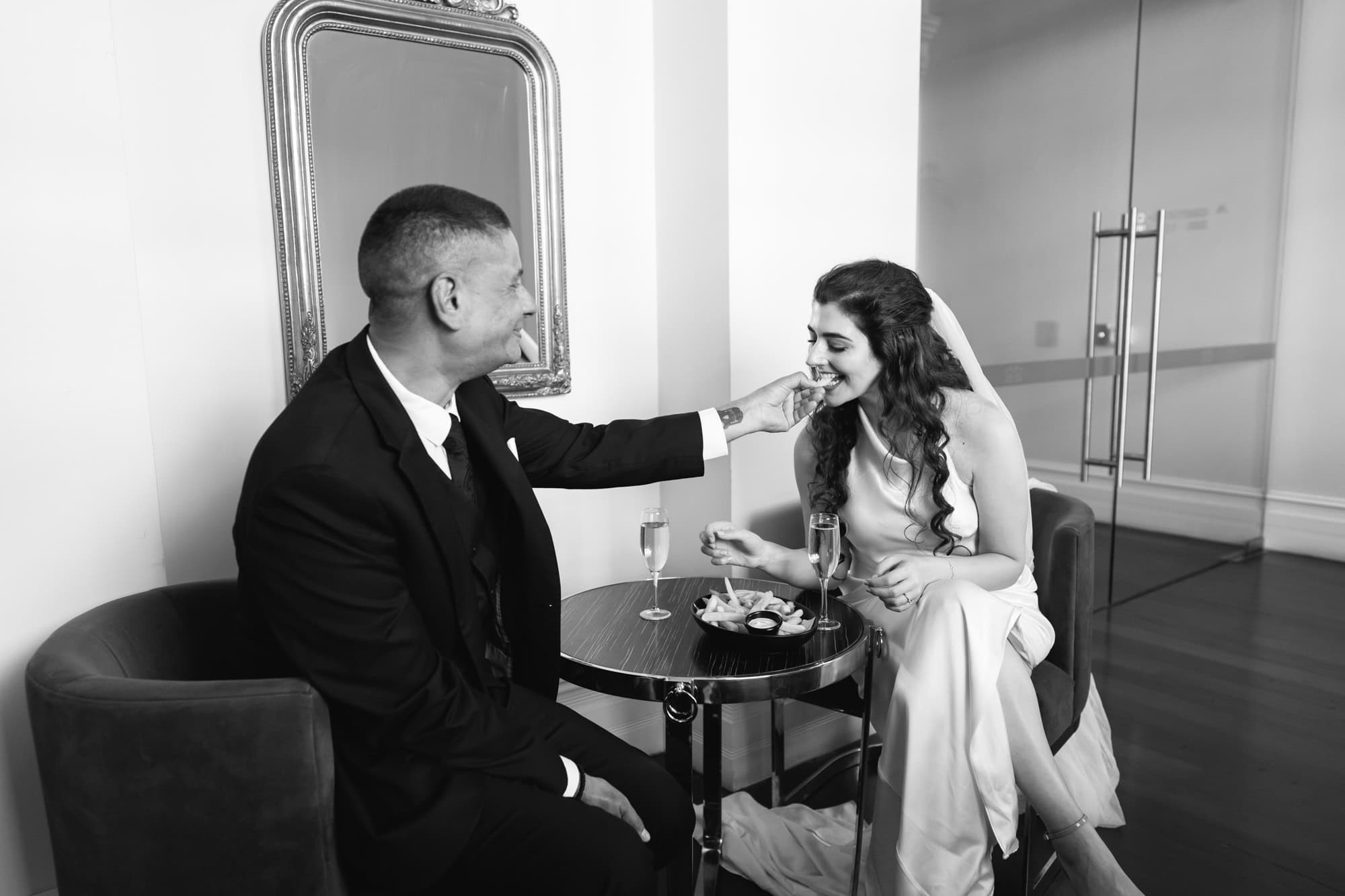 wedding photos Perth groom in black suit feeding hot chips to bride