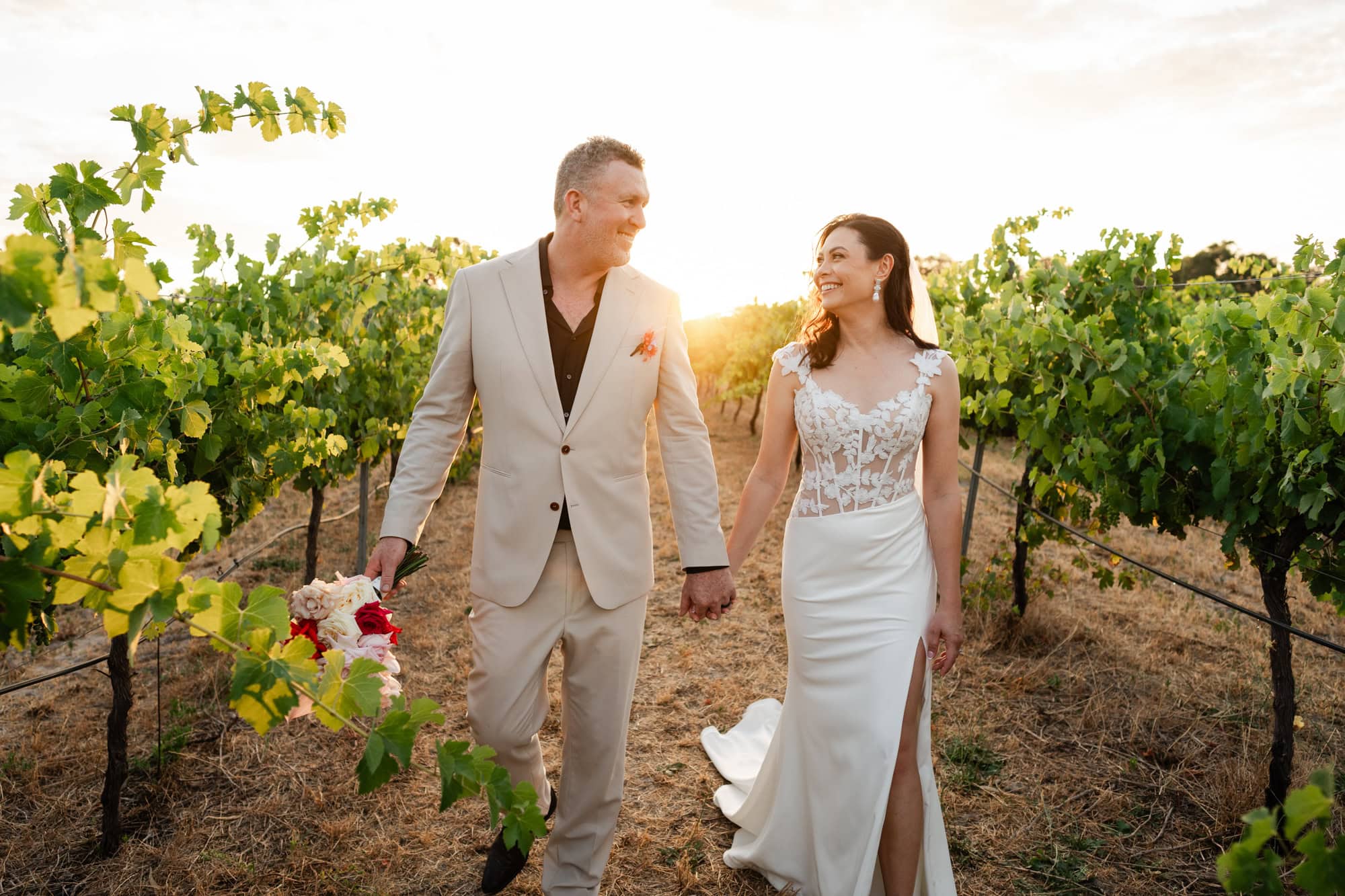 wedding photos Perth bride and groom walking through vineyard at sunset