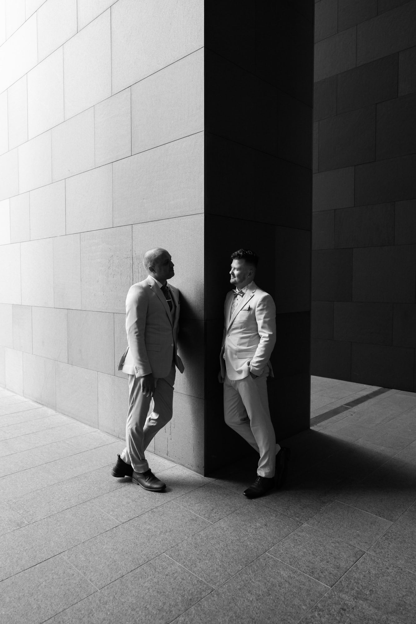 wedding photos Perth two grooms wearing suits leaning against wall