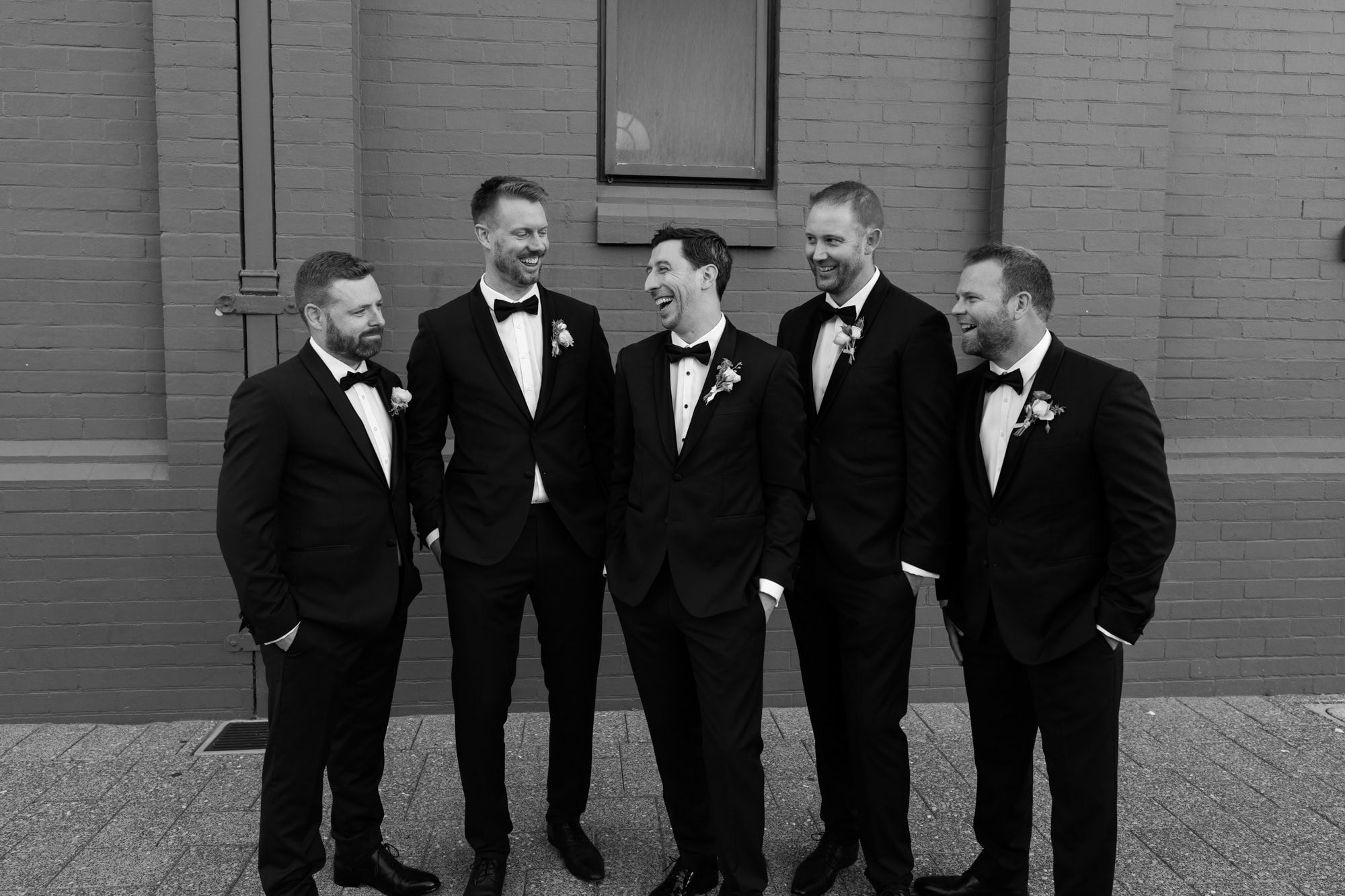 wedding photos Perth groom wearing black suit standing with groomsmen laughing