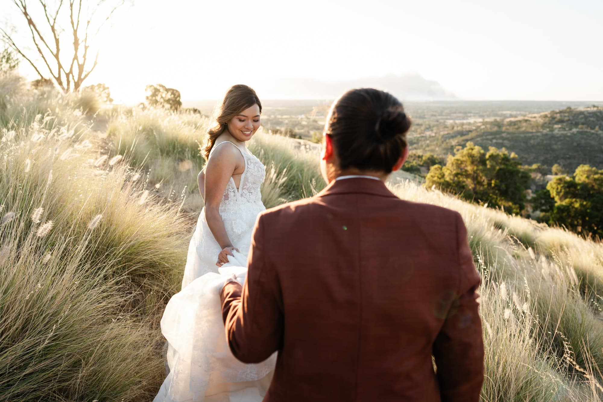 wedding photos Perth bride wearing maroon suit carrying bottom of dress of bride