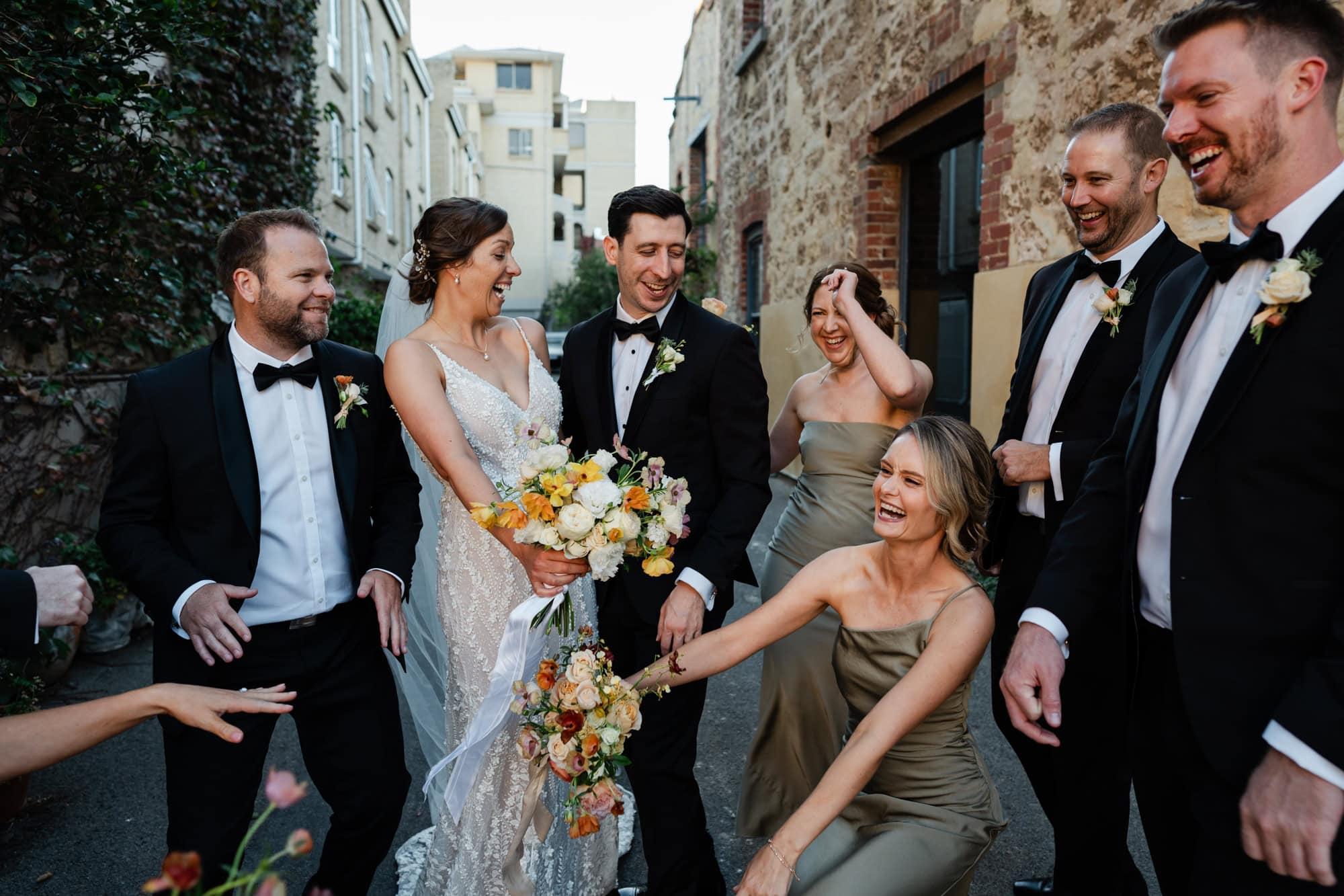 wedding photos perth wedding party with groomsmen wearing black suit and bridesmaids in green dresses dancing and laughing in circle at Perth wedding