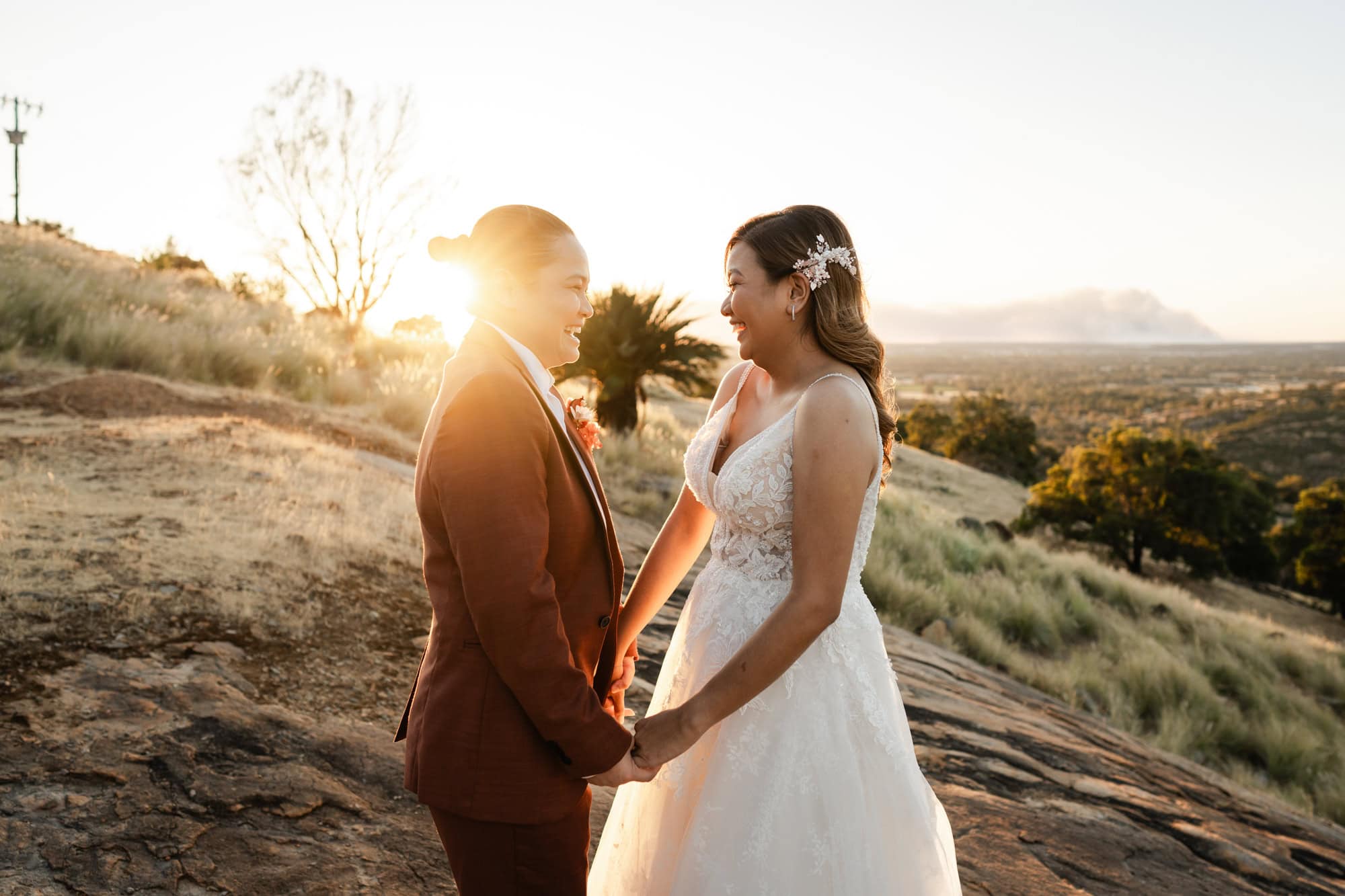 wedding photos Perth bride wearing red suit holding hands with bride wearing white dress laughing at sunset