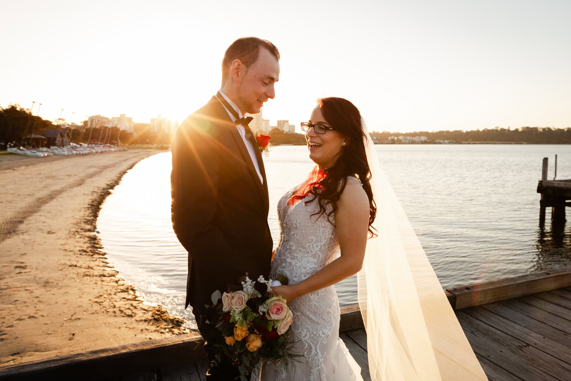 wedding photos Perth bride and groom laughing on jetty in Perth at sunset